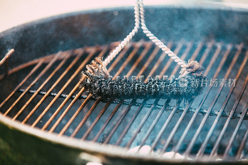 Man using brush to clean barbecue grill